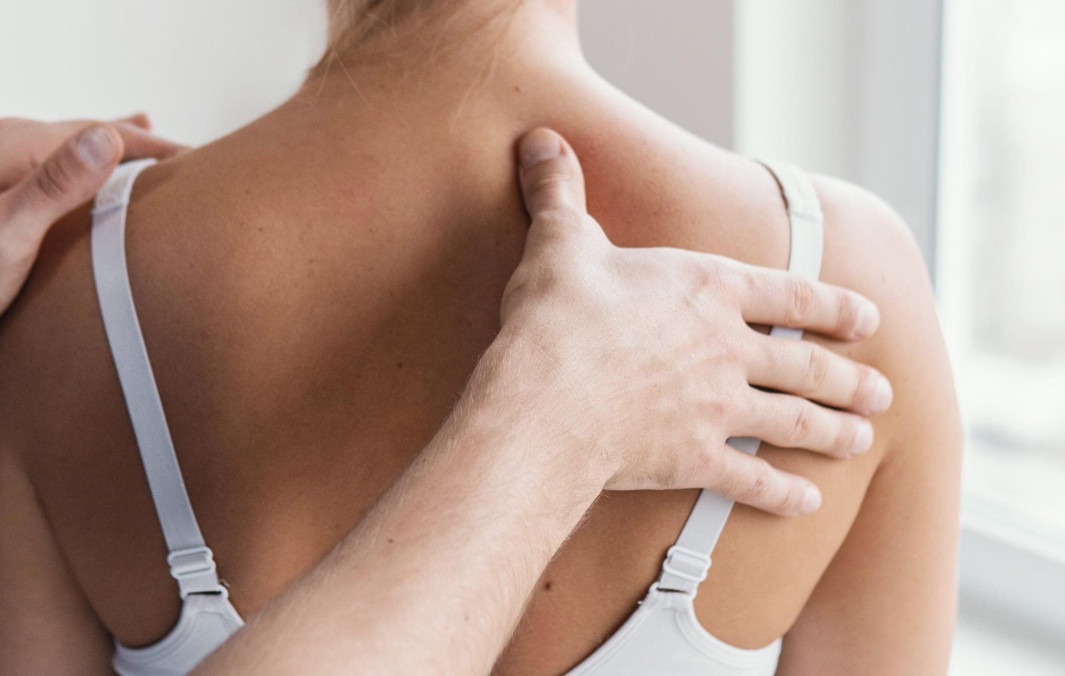 Manuelle Therapie: Ein Physiotherapeut behandelt Schulter und obere Wirbelsäule einer Patientin